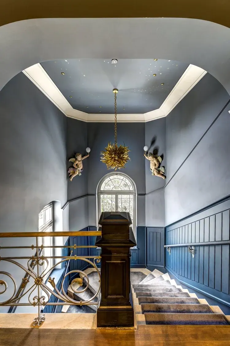 Historisches Treppenhaus mit blauen Wandflächen, Sternenhimmel und goldener Leuchte