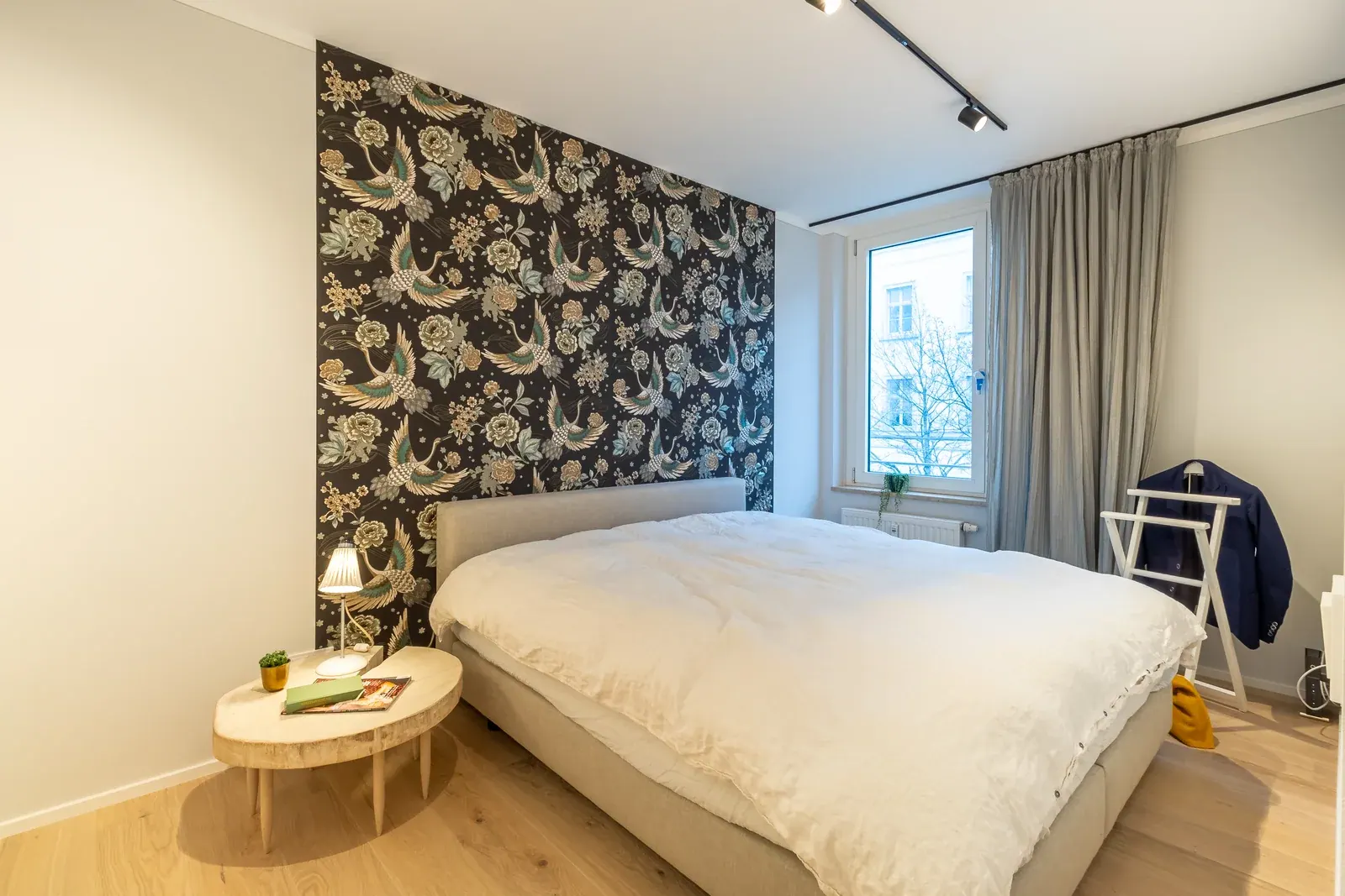 Schlafzimmer mit floraler Vogeltapete und hell gestrichenen Wänden