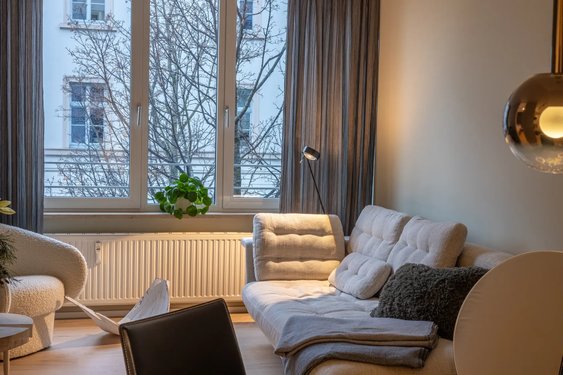 Wohnzimmer mit hellem Sofa, abgestimmten Gardinen und großer Fensterfront